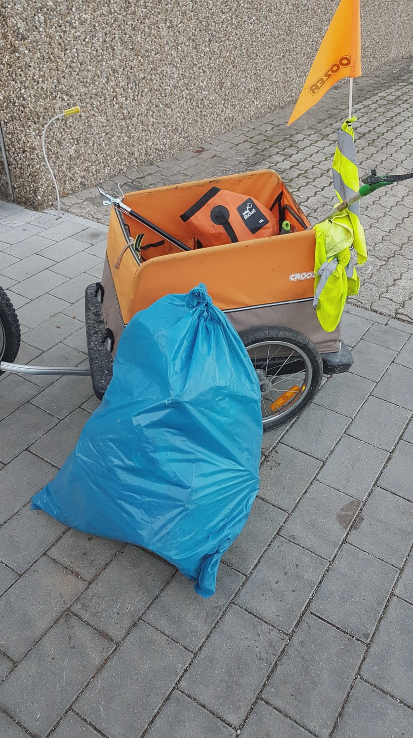 Ein voller Müllsack steht vor dem Fahrradanhänger.