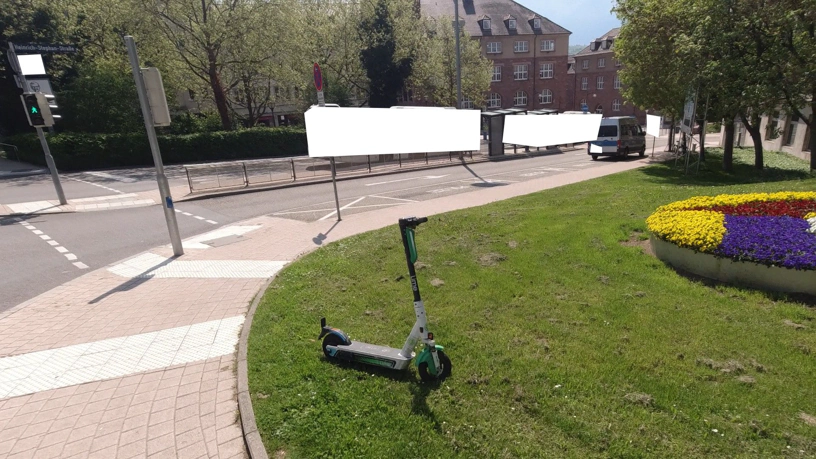 Der selbe E-Roller wurde auf den Rasen gestellt, wo er keine Gefahr mehr darstellt.