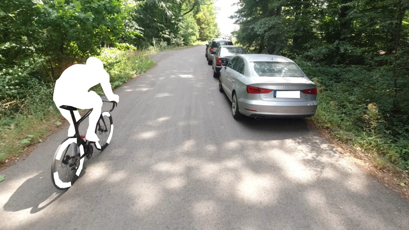 Rennradfahrer überholt mich links. Rechts geparkte Fahrzeuge.