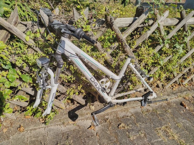 Fahrrad ohne Reifen und andere Dinge hängt an einem Zaun.