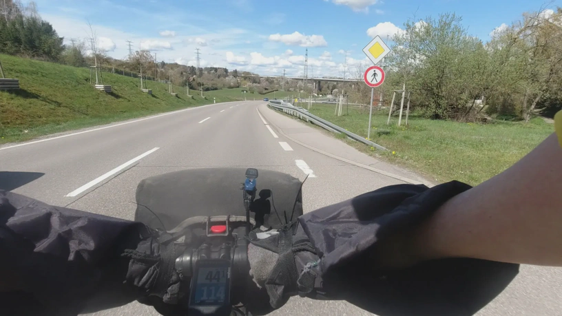 Foto aus dem nach vorne gerichteten Video der Kamera am Brustgurt. Landstraße. Rechts ein beginnender Gehweg mit der Beschilderung 'Fußgänger verboten'.