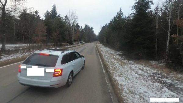 Ein Auto steht auf der Landstraße; rechts ca. 1 Meter Platz zwischen Auto und Straßenrand. Es liegt etwas Schnee.